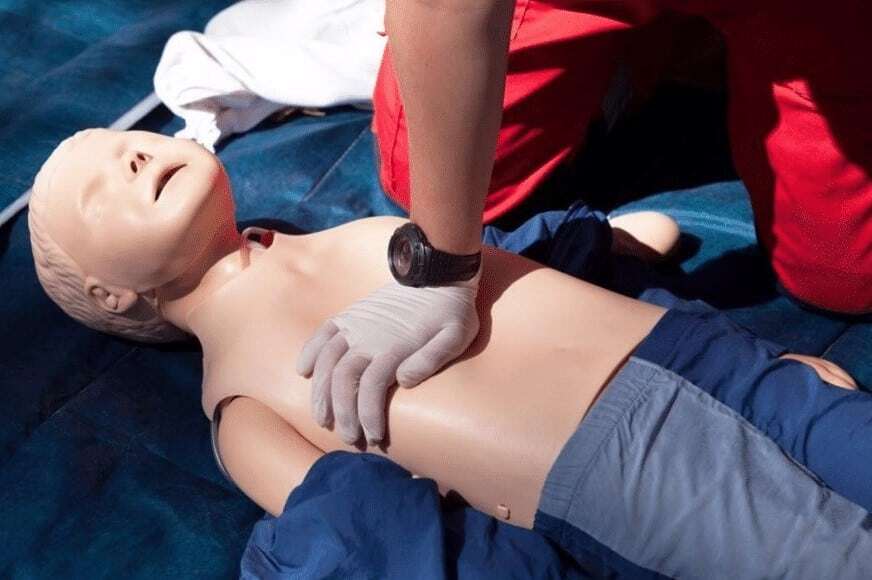 “Rescuer administers CPR to child.”