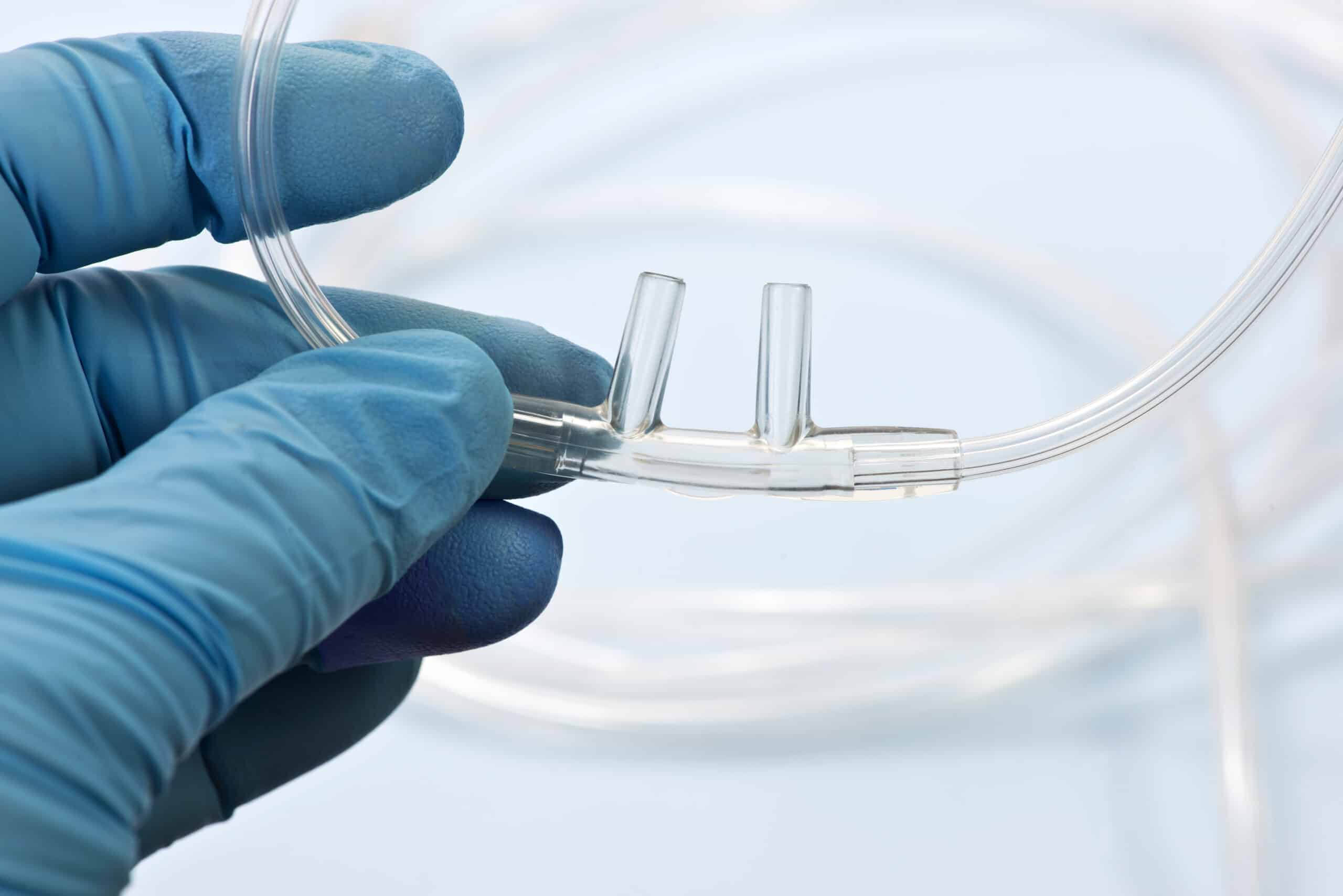 Nasal cannula held by a gloved hand.