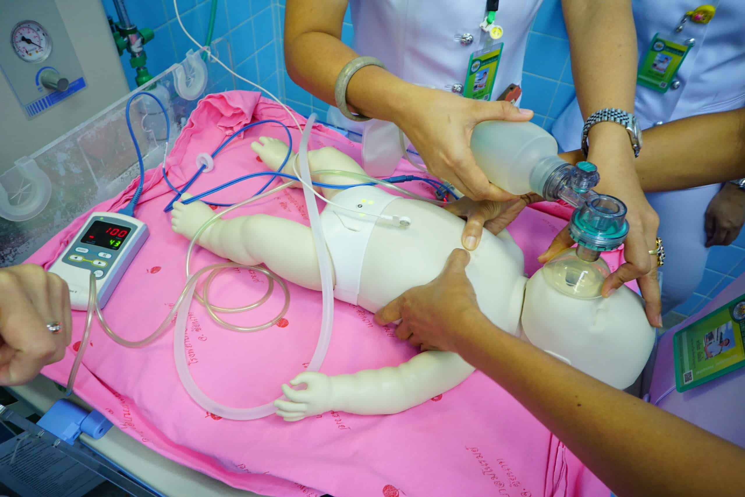 Medical staff positioned around an infant’s medical bed.